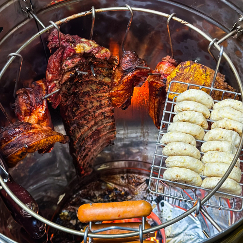 Interior del barril asador de 13 Kg con costillas, pollo y chorizos colgados de los ganchos